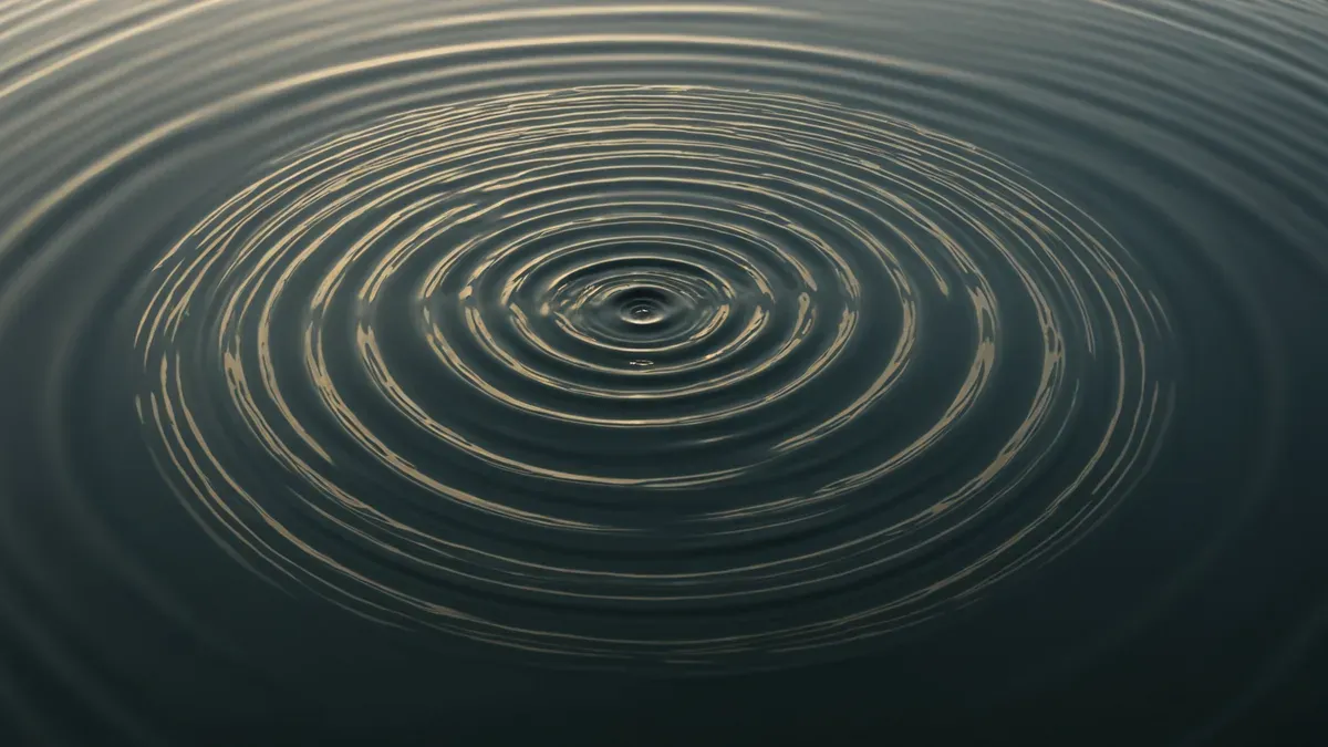 Ondes circulaires concentriques à la surface d'une eau sombre, autour du point d'impact d'une goutte
